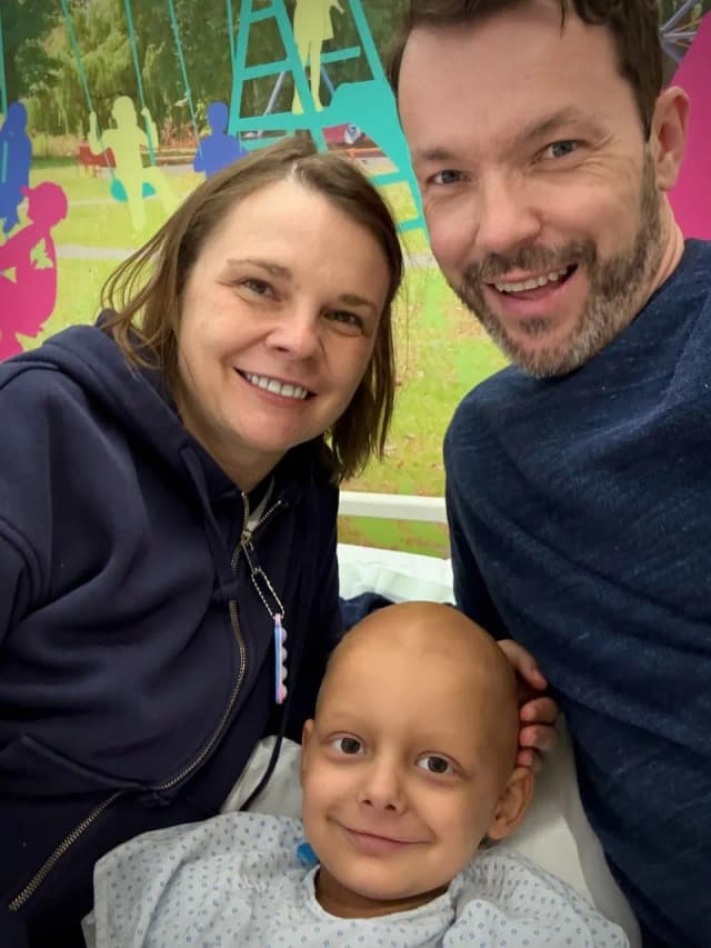 Aleks with his parents in the hospital, smiling bravely before his major surgery.