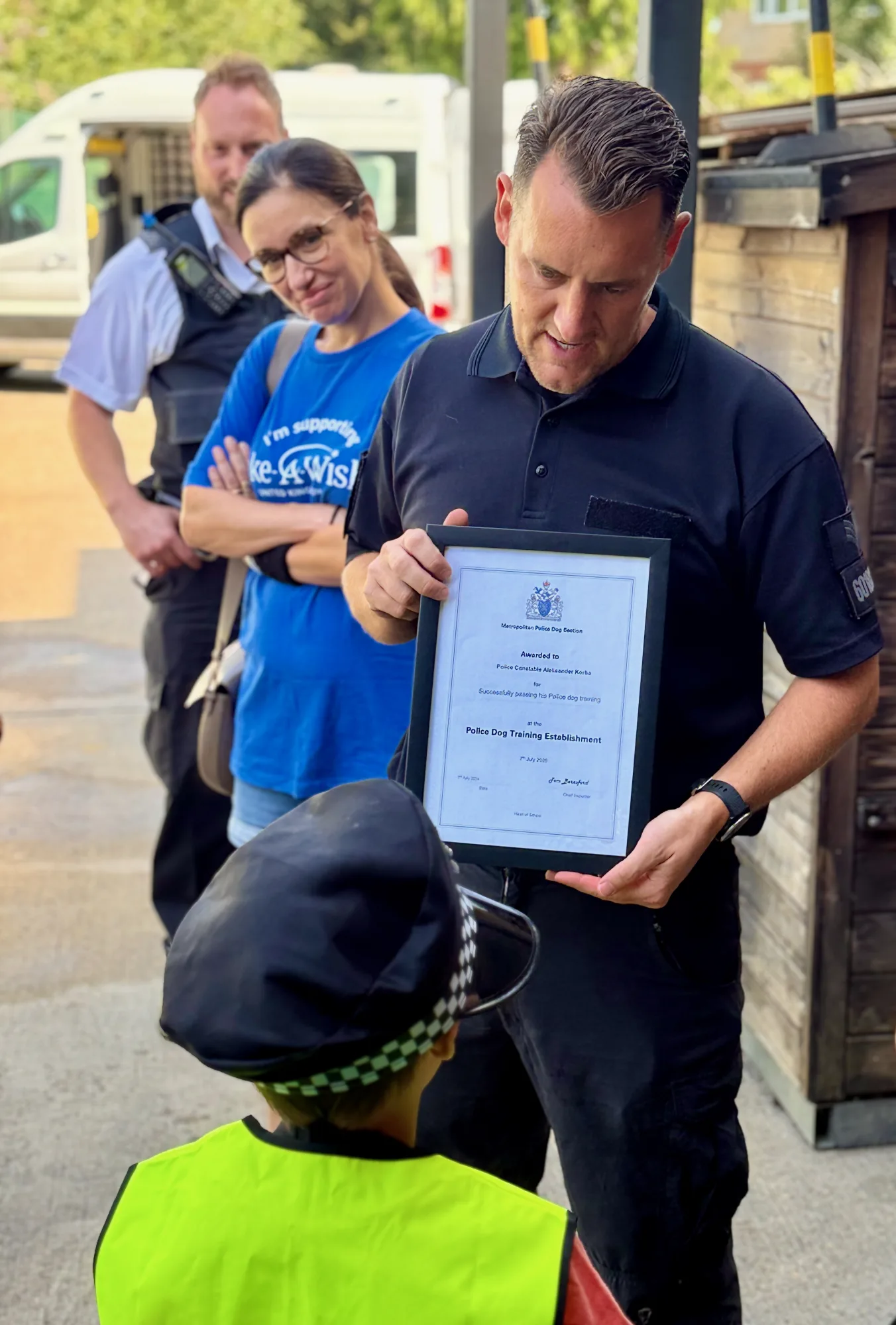 Presented with his Metropolitan Police Dog Section certificate for passing his police-dog training, watched by a Make-A-Wish representative. 🎓