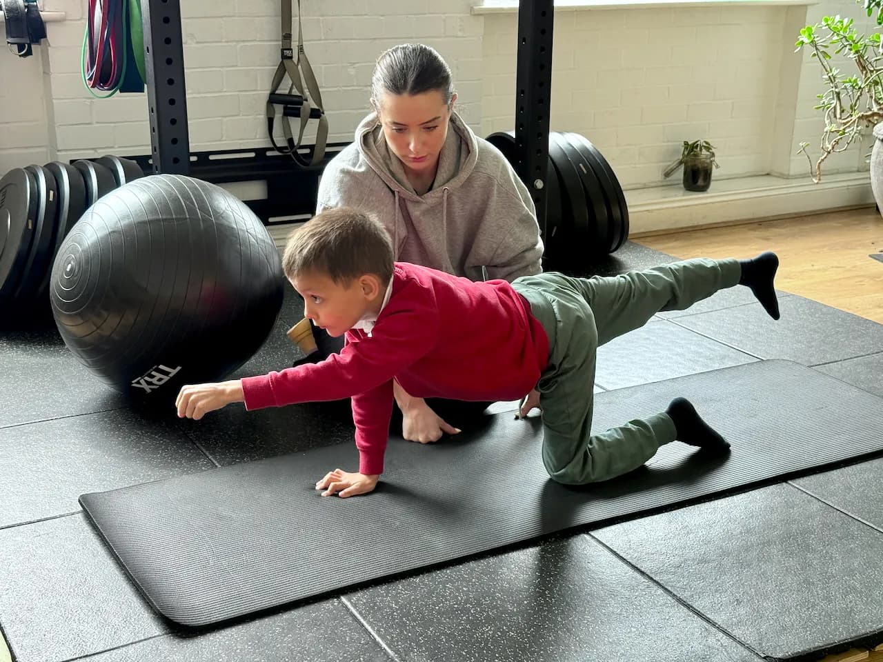Aleks in a bird-dog hold on the mat - Gabi checking his technique as he reaches out front, working core stability and control.
